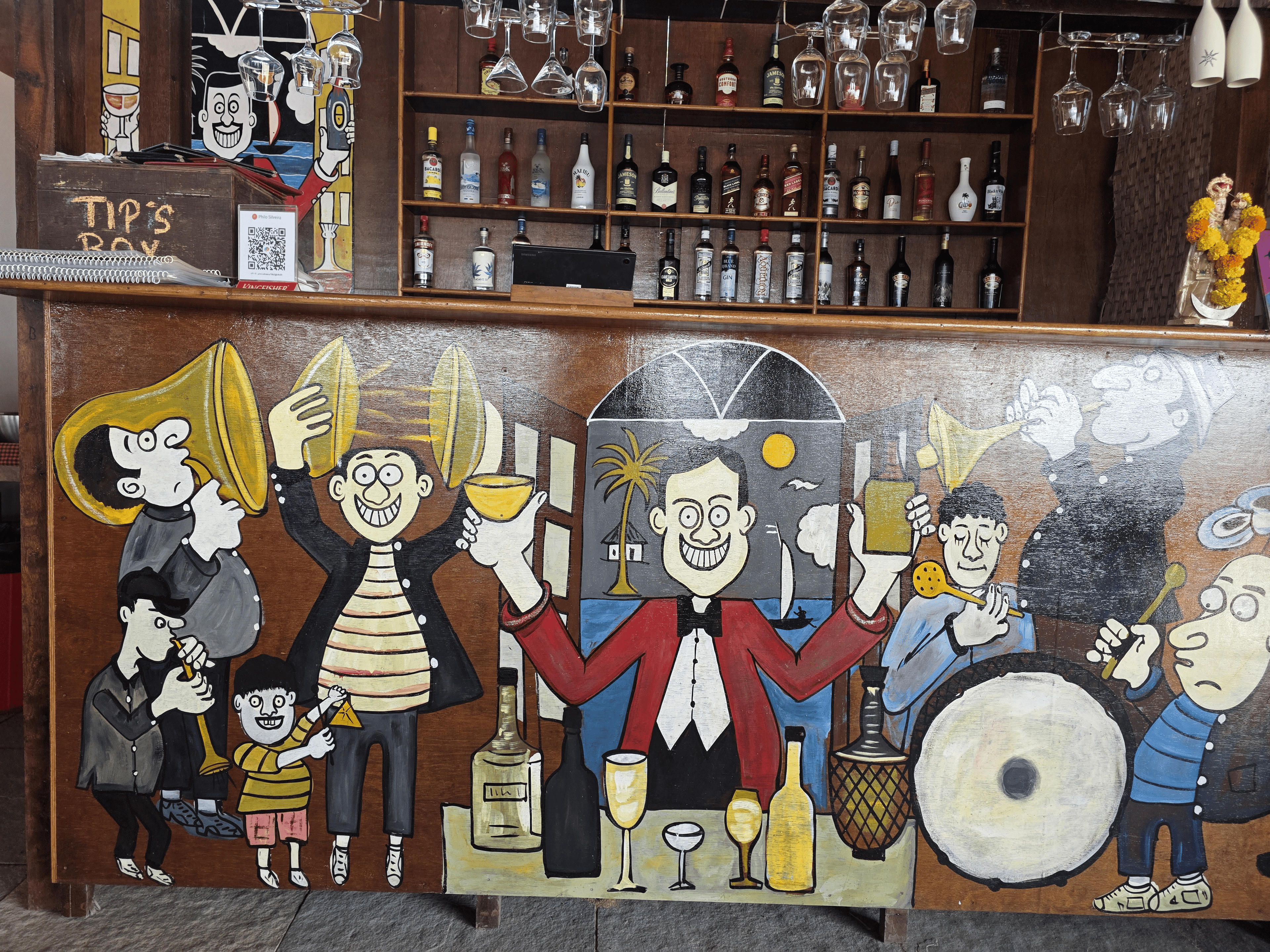 Hand-painted bar mural featuring lively characters celebrating with drinks, spirits shelf behind